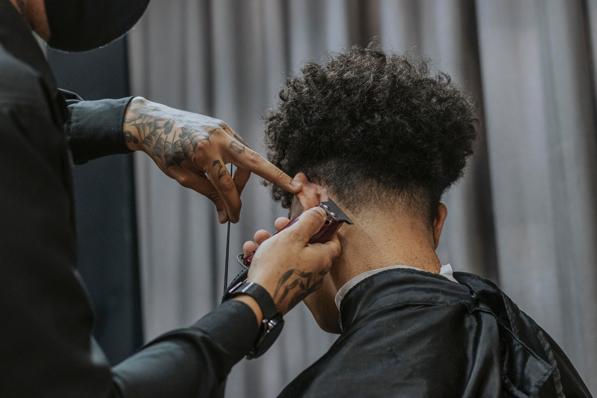 Back View of a Man with Curly Hair Getting His Hair Shaved
